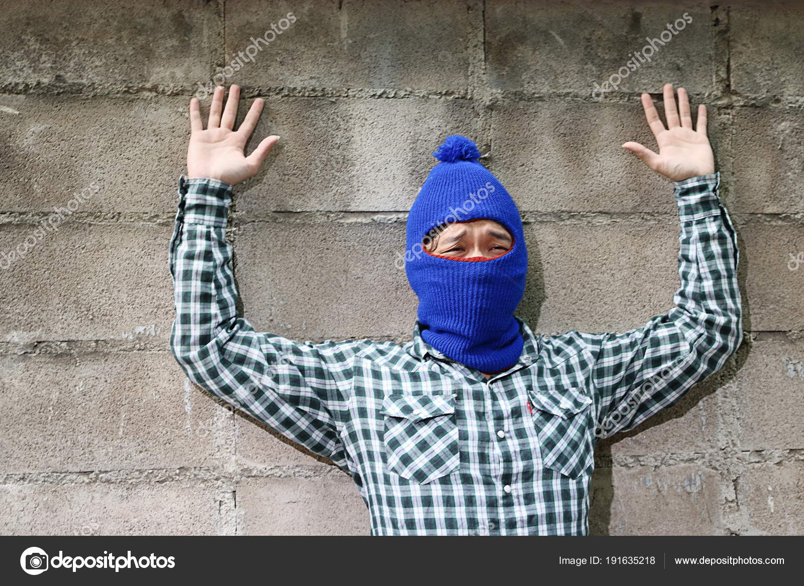 Thief stop and put hands up against brick wall background. Catch