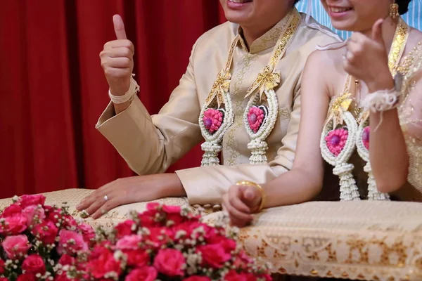 Feliz tiempo de novia y novio mostrando el signo de golpe en la ceremonia de boda tradicional tailandesa . — Foto de Stock