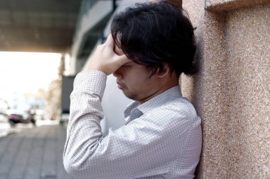 Depresyonda ve Asya iş adamı elle duvara yaslanmış alnına vurguladı