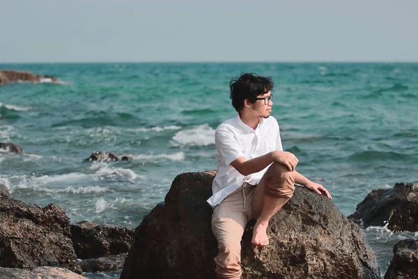 Ung asiatisk man avkopplande på vagga av seashore — Stockfoto