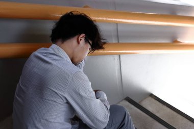 Şiddetli depresyon depresif genç Asya iş adamı arka görünümü.