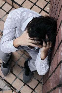 Yüz eller ve cry dokunmadan endişeli stresli genç Asya iş adamı havadan görünümü.