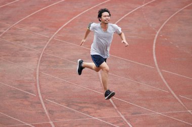 Stadyumda yarış pisti üzerinde koşan genç atlet Asya adam. Sağlıklı aktif yaşam tarzı kavramı.