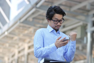 Seyir mobil akıllı telefon ve Kentsel şehir arka plan el yetiştirme başarılı genç Asya iş adamı.