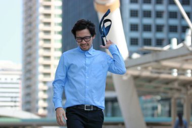 Yürüyüş ve onun kravat içinde kentsel atma sinirli stresli genç Asyalı işadamı şehir arka bina.