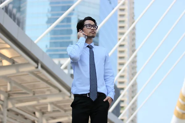 Confiado joven asiático hombre de negocios hablando por teléfono en el edificio urbano fondo de la ciudad . — Foto de Stock