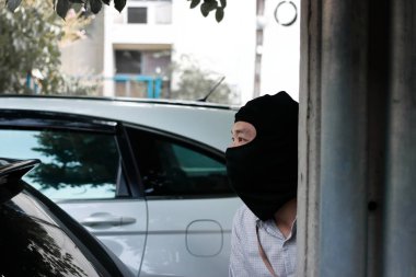 Siyah kar maskeli bir hırsız arabaya girmeye çalışıyor. Suç konsepti.