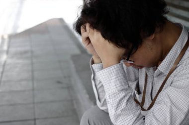 Tired stressed young Asian business man in depression with hands on forehead