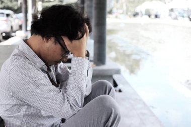 Side view of disappointed Asian business man suffering from stress or headache