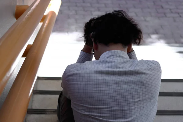 Voltar visão de frustrado exausto asiático homem de negócios em depressão com as mãos no rosto sentado ao ar livre . — Fotografia de Stock