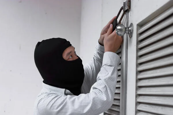 Maskerad tjuv i svart balaclava försöker bryta in i hus — Stockfoto