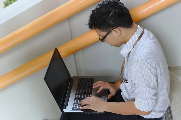 Tampilan samping dari pria bisnis Asia muda menggunakan laptop komputer — Stok Foto