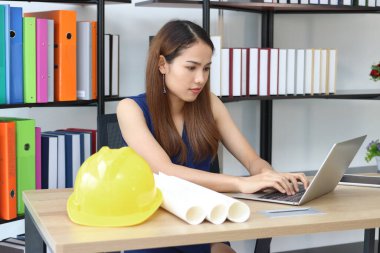 Çekici Asyalı iş kadını ofiste dizüstü bilgisayarla çalışıyor..