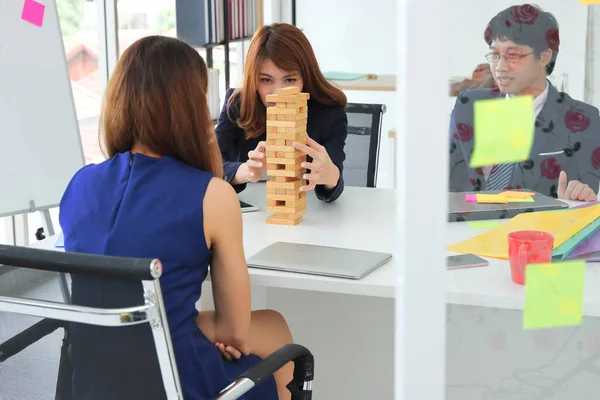 Thoughtful and mindful group of business people playing wooden block tower  in office. Risk and strategy business concept.