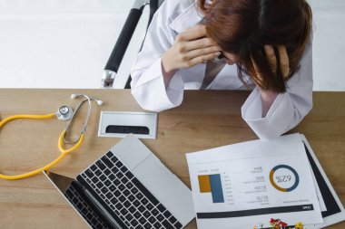 Yorgun, genç Asyalı doktor elleri yüzü üzerinde işyerinde ağır depresyon geçiriyor..