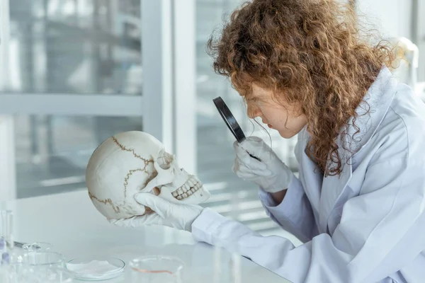 Genç bilim adamları laboratuvarda insan kafatasını inceliyor..