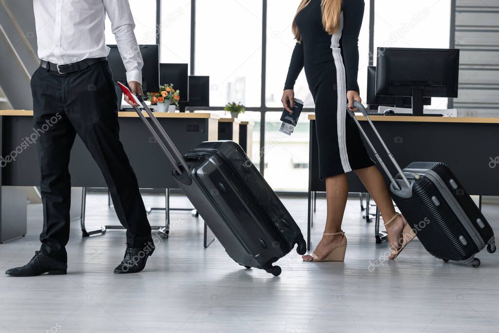 Cropped image of business people holding passport and luggage in workplace of office. Summer vacations concept.