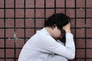 Depresyonda olan Asyalı genç bir adamın yan görünüşü.