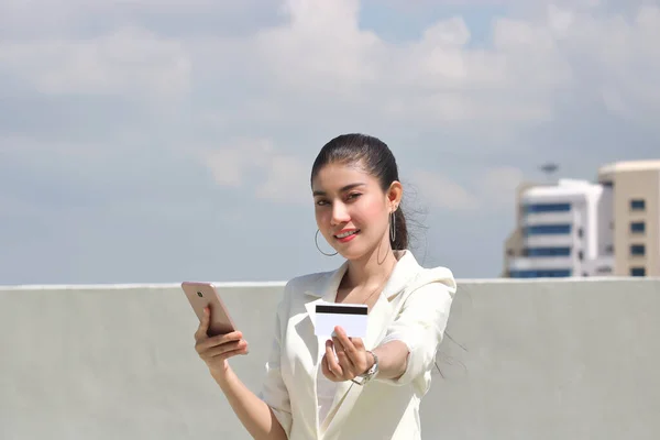 Smiling young Asian woman with mobile smart phone and credit card for shopping online.