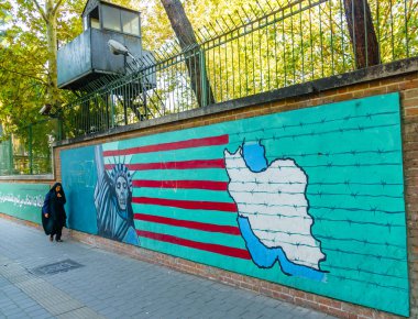 TEHERAN, IRAN - NOVEMBER 05, 2016: Iranian propaganda mural at the wall of former US embassy and veiled woman clipart