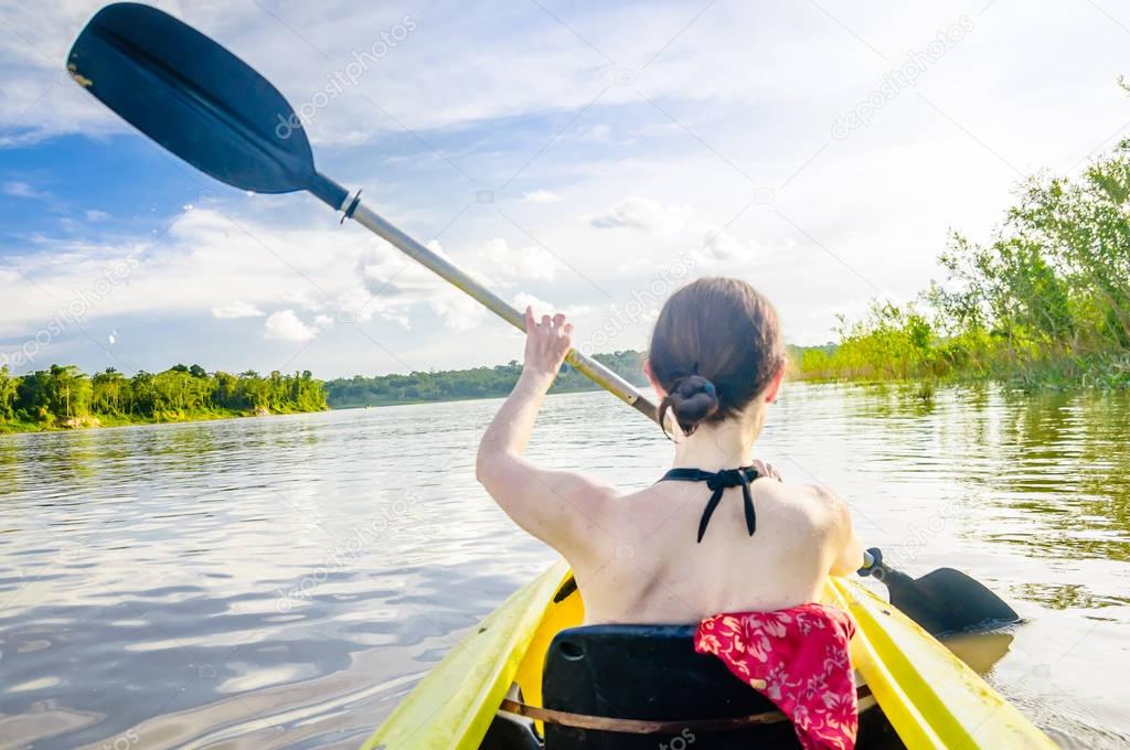 Girl riding kayak on Amazon river by Leticia in Colombia