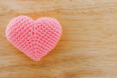 Ahşap zemin üzerinde iplik ile örülmüş pembe kalp.