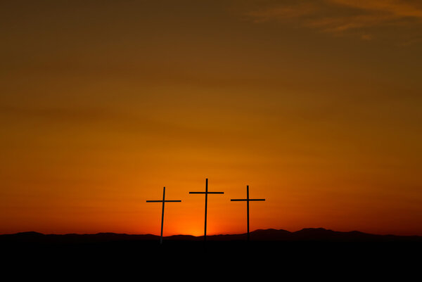 Three crosses on a hill over bright sunset with copy space