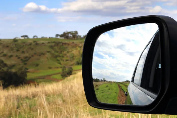 Road in the car mirror rural scene
