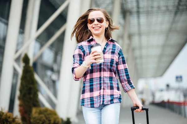 Conceito de viagem aérea com jovem empresária hipster em camisa xadrez com mala e xícara descartável com café ou chá. Liberdade de viagem e conceito de férias . — Fotografia de Stock