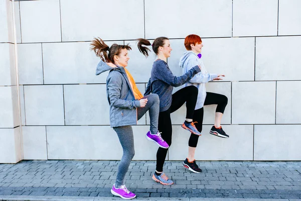 Altura completa de três mulheres esportivas cara a cara se exercitando para maratona e fitness treino — Fotografia de Stock