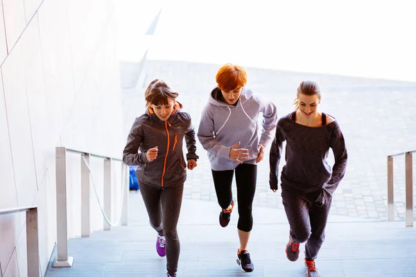 Grupo de três mulheres atléticas correndo escadas acima durante o treinamento cardio-intervalado . — Fotografia de Stock