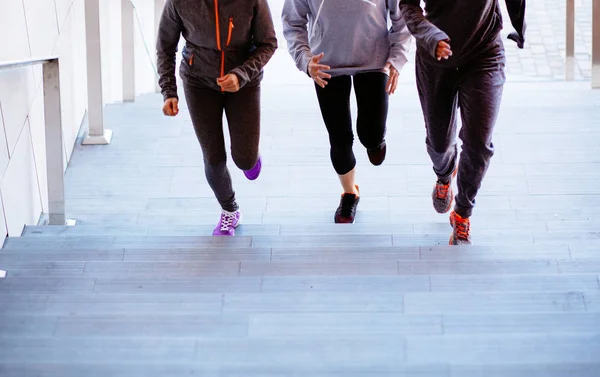 Grupo de três mulheres atléticas correndo escadas acima durante o treinamento cardio-intervalado. Fechar, vista frontal . — Fotografia de Stock