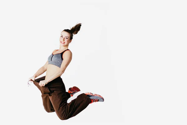 Beautiful young sports woman jumping with big jeans, isolated on white — Stock Photo, Image