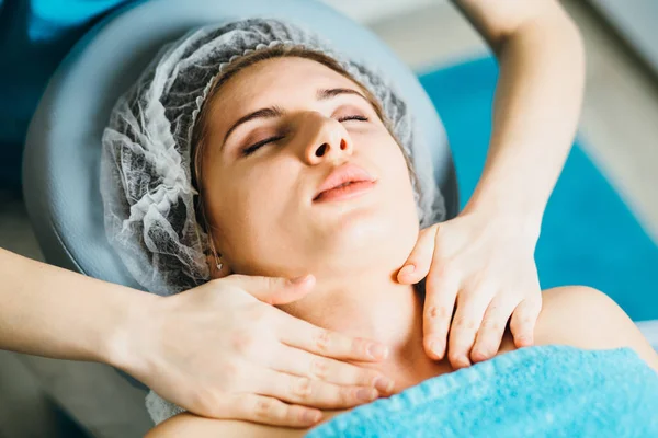 close up of beautician doctor with patient in spa wellness center. Professional cosmetologist make body shoulders and face relaxing massage to indian girl in cosmetology cabinet or beauty parlor.