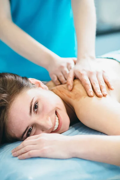 Close-up van de jonge vrouw liggend vestured turquoise handdoek terwijl massagetherapeut masseren van haar schouders. Beauty, gezondheid leven en cosmetologie concept. — Stockfoto