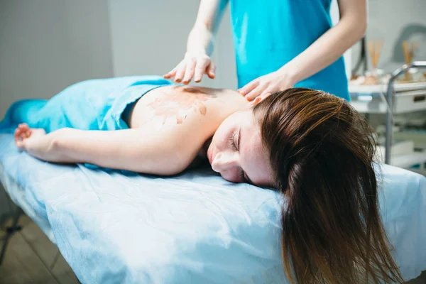 Close-up van de jonge vrouw liggend vestured turquoise handdoek terwijl massagetherapeut masseren van haar schouders. Beauty, gezondheid leven en cosmetologie concept. — Stockfoto