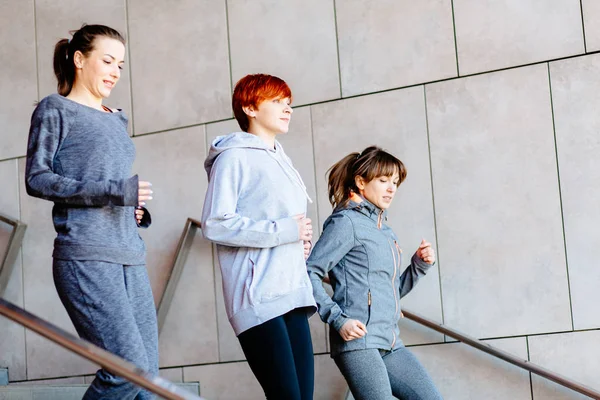 Πλάγια άποψη τριών γυναικών γυμναστήριο τρέξιμο στις σκάλες. Υγιεινού τρόπου ζωής, της φιλίας και αθλητισμού έννοιες — Φωτογραφία Αρχείου