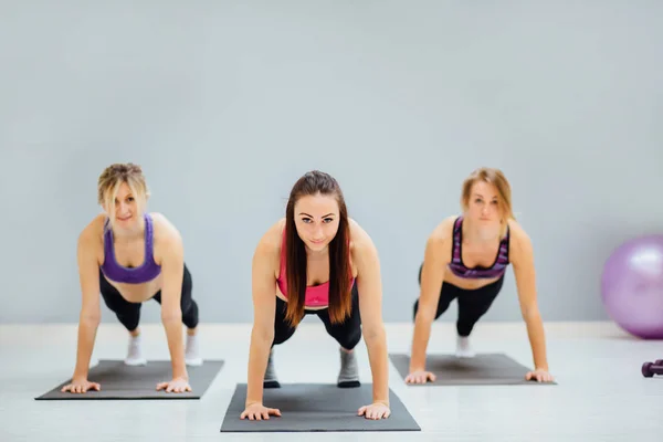 Группа из трех молодых женщин, работающих в фитнес-студии . — стоковое фото
