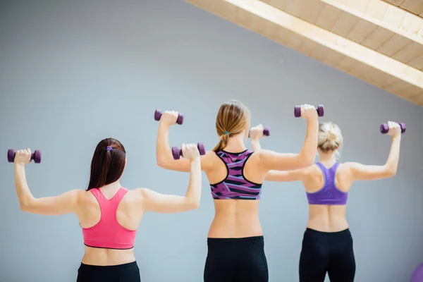 Группа из трех женщин делает упражнения с гантелями в фитнес-студии . — стоковое фото