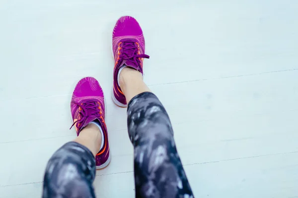 Vista superior de la mujer fitness sentada en el piso blanco en el estudio. Deporte, dieta y concepto de vida saludable . — Foto de Stock