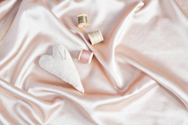 Araçlar - iğneler, kalp yastık dikiş ahşap iş parçacığı üzerinde Bej Saten ya da ipek arka plan bobinler