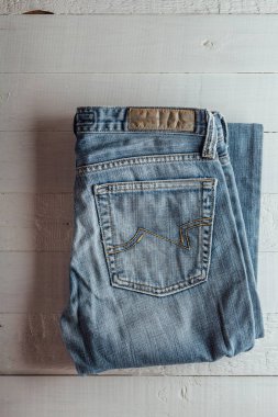 Mavi jeans Beyaz ahşap arka plan üzerinde katlanmış. Mavi jeans Tekstil arka cepler