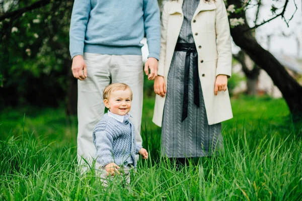 Cute toddler boy learning to walk and making first steps while his father and mother stands behind from him. — Stock Photo, Image