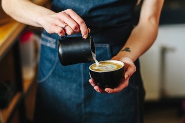 Kafede kahve latte veya kapuçino sanat yapma kadın barista'nın el yakın çekim.