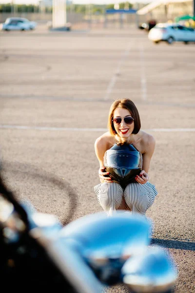Привлекательная женщина-байкер сидит на корточках за своим мотоциклом . — стоковое фото
