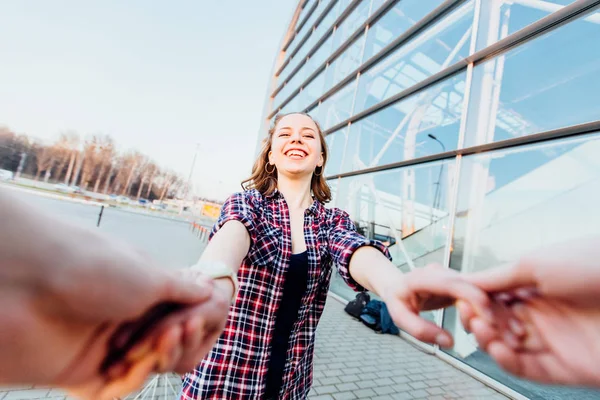 Hombre irreconocible girando joven hipster mujer por las manos. jóvenes dando vueltas tomados de la mano cerca del fondo urbano. euforia — Foto de Stock