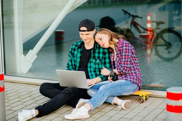 Feliz joven pareja hipster sentado en el suelo y utilizando el ordenador portátil — Foto de Stock