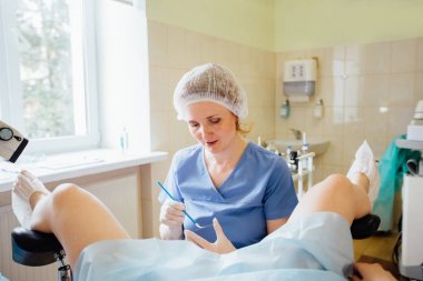 Gynecology consultation. Female doctor taking analysis of pregnant woman. Real people models. clipart