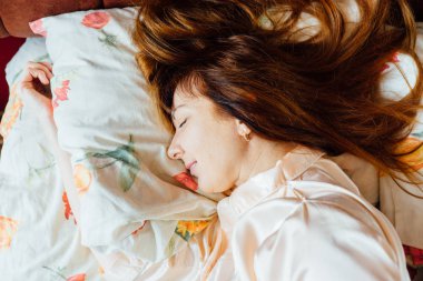 Kızıl saçlı güneşli sabah yatakta uyuyan güzel orta yaşlı kadının Üstten Görünüm.