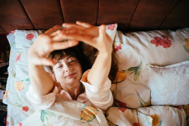 Pijama Kızıl kahverengi saçlı sevimli orta yaşlı kadın üst görünümünü yavaş yavaş yatakta uyanmak.